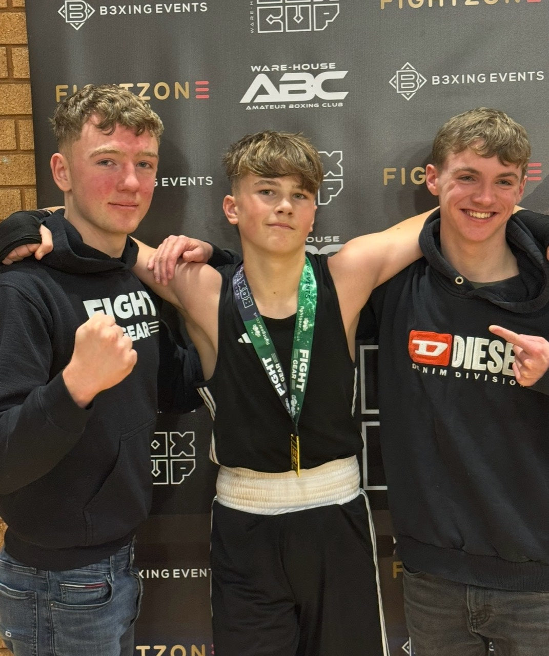 Kaelan Brown at a boxing event with a medal and two companions